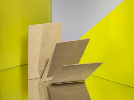 Panneau MDF INFINITE TRICOYA® FINSA. Photo d'ambiance avec 3 panneaux marrons sur un fond de couleur jaune-vert.