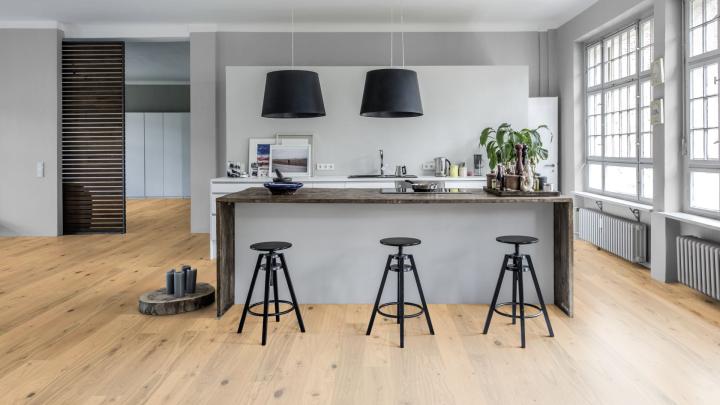 Parquet contrecollé dans une cuisine. 3 tabourets sont devant le plan de travail. 