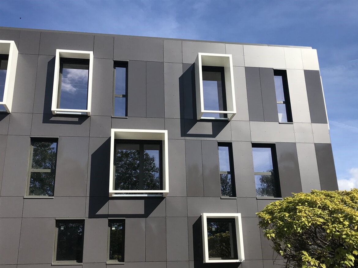 Extérieur d'un bâtiment. Panneaux de façade gris et contours des fenêtres en relief blanc