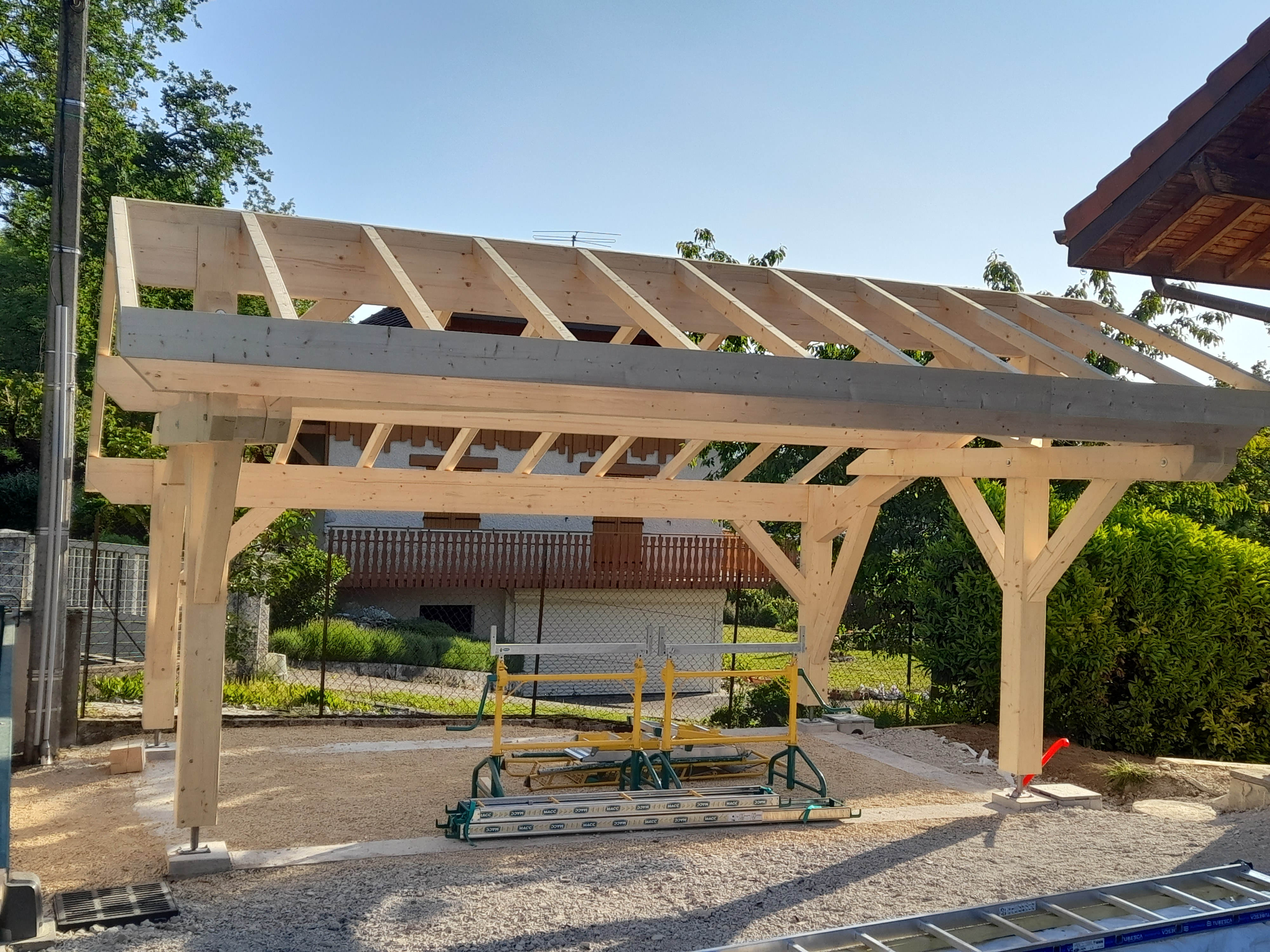 Construction d'un carport en bois dehors. La couleur de la charpente et des poteaux sont de couleur clairs