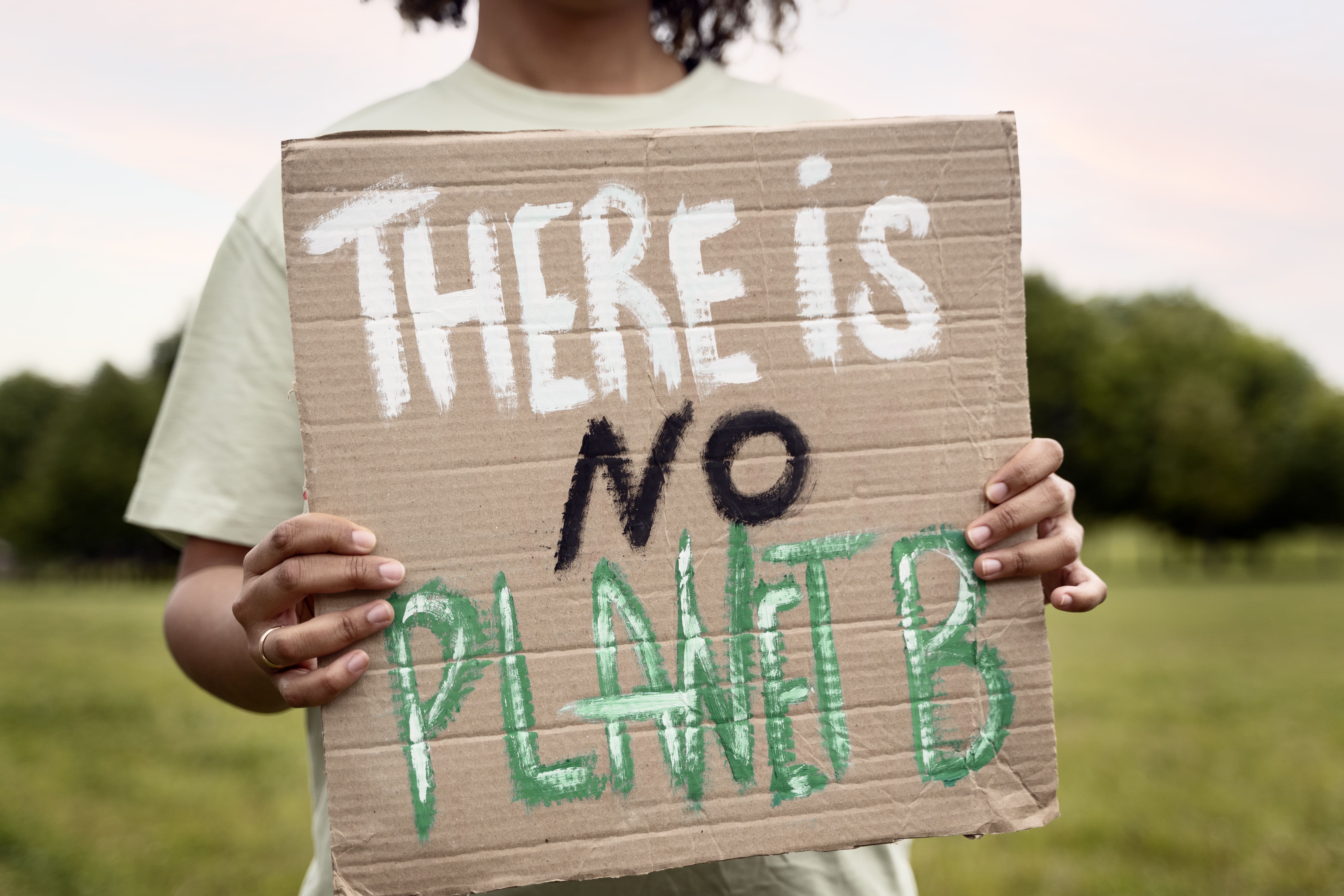 Un Homme qui tient une pancarte en carton om il est mentionné "There is no planet B" en anglais, signifiant "Il n'y a pas de planète B"