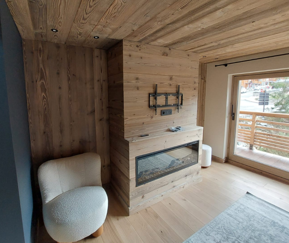 Lames de lambris en vieux bois dans un salon au mur et au plafond, créant un chalet au décor chaleureux et accueillant.