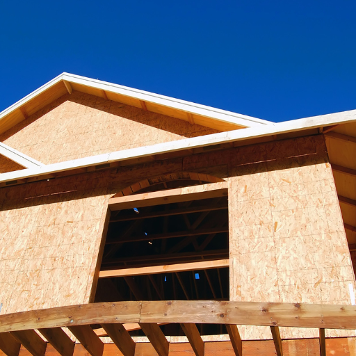 Réalisation d'une maison. Des panneaux OSB sont utilisés. Chantier en cours. Le ciel derrière est bleu.