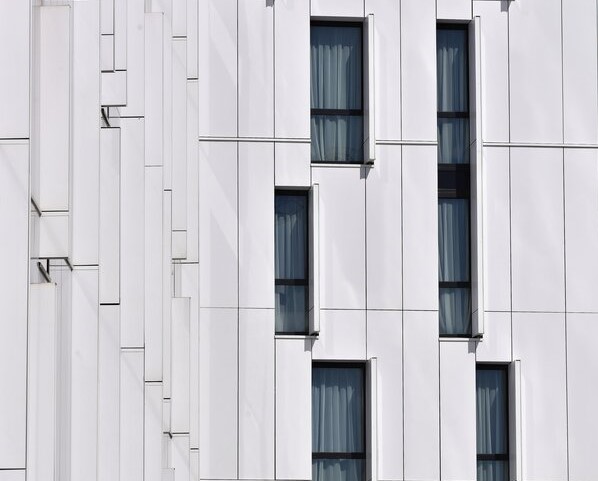 Façade d'un bâtiment. Panneaux de façade blancs et des vitres aux contours noirs. 