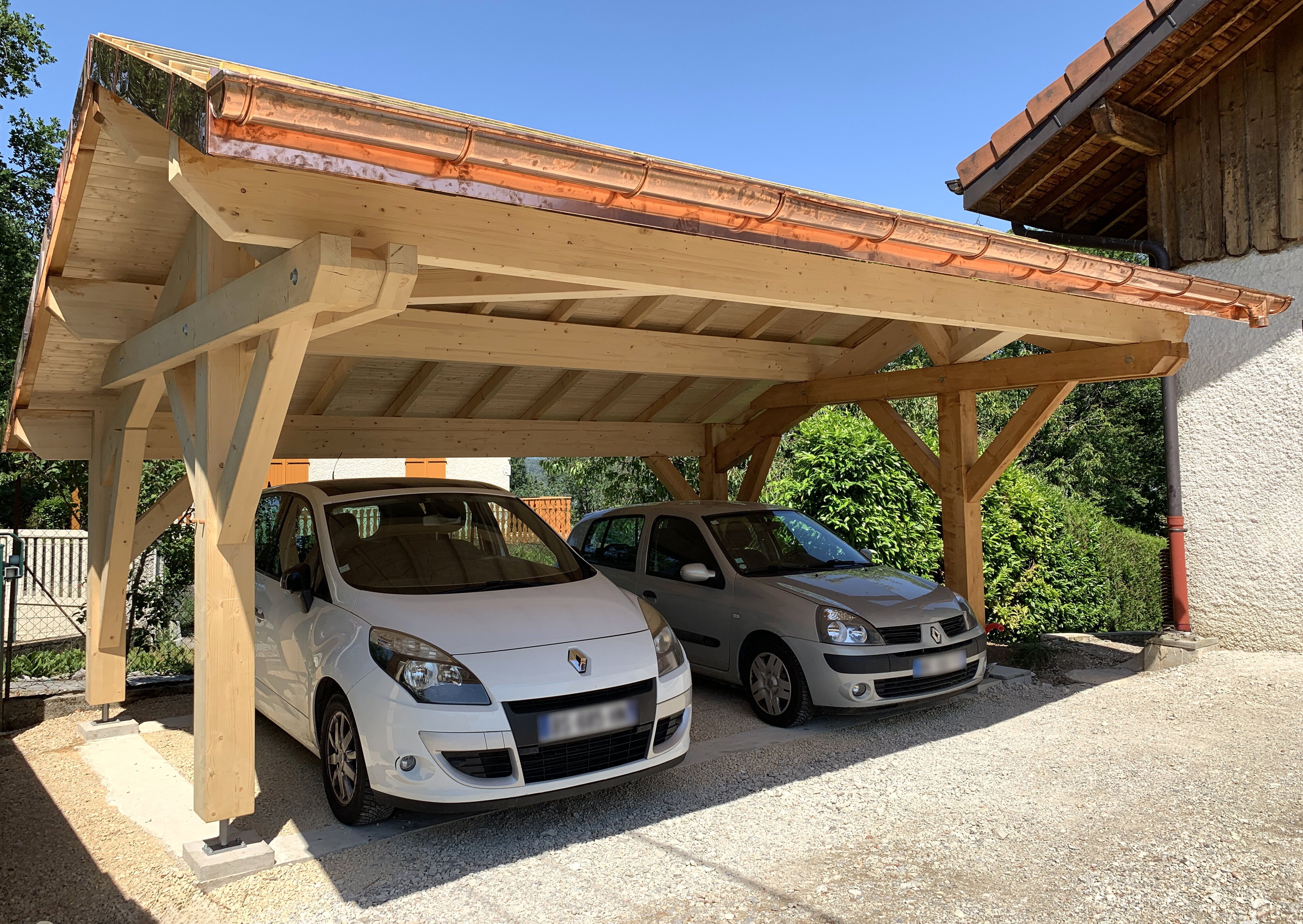 Réalisation carport 2 place offre premium. 2 voitures sont garées et abritées. La couleur du bois du carport est clair.