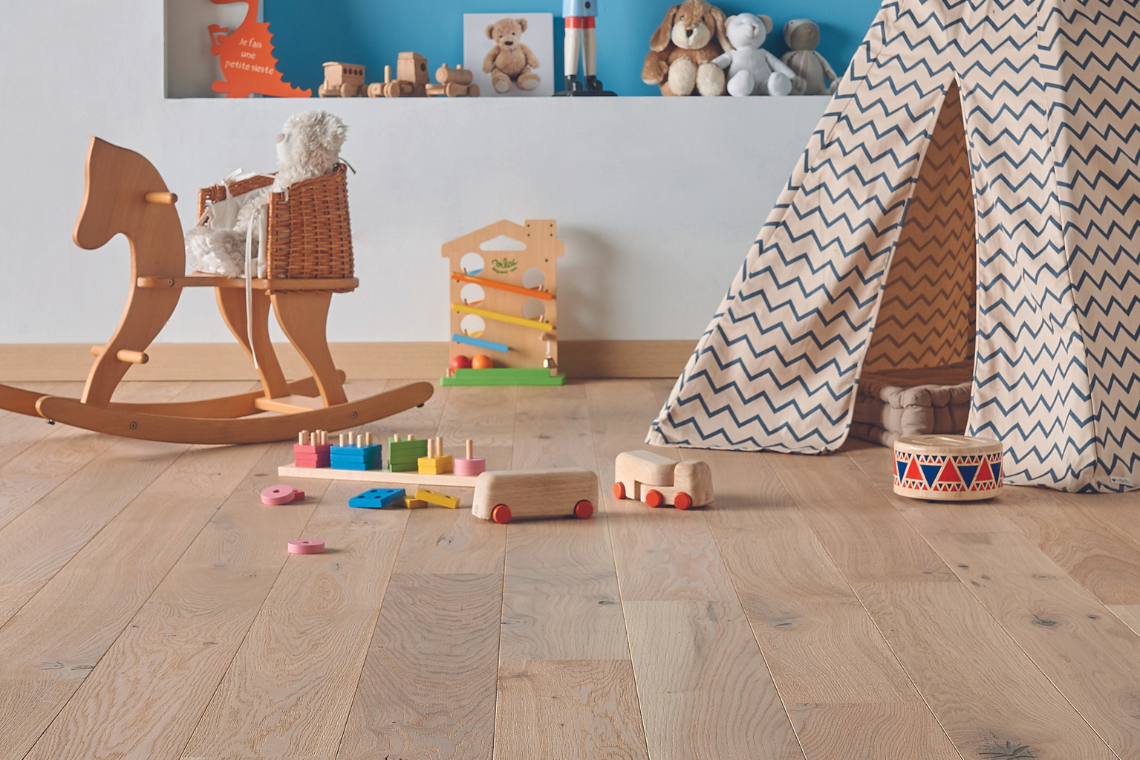 Chambre d'enfants avec un parqet contrecollé clair. Un tipie orne le sol ainsi que des jouets en bois pour enfants.